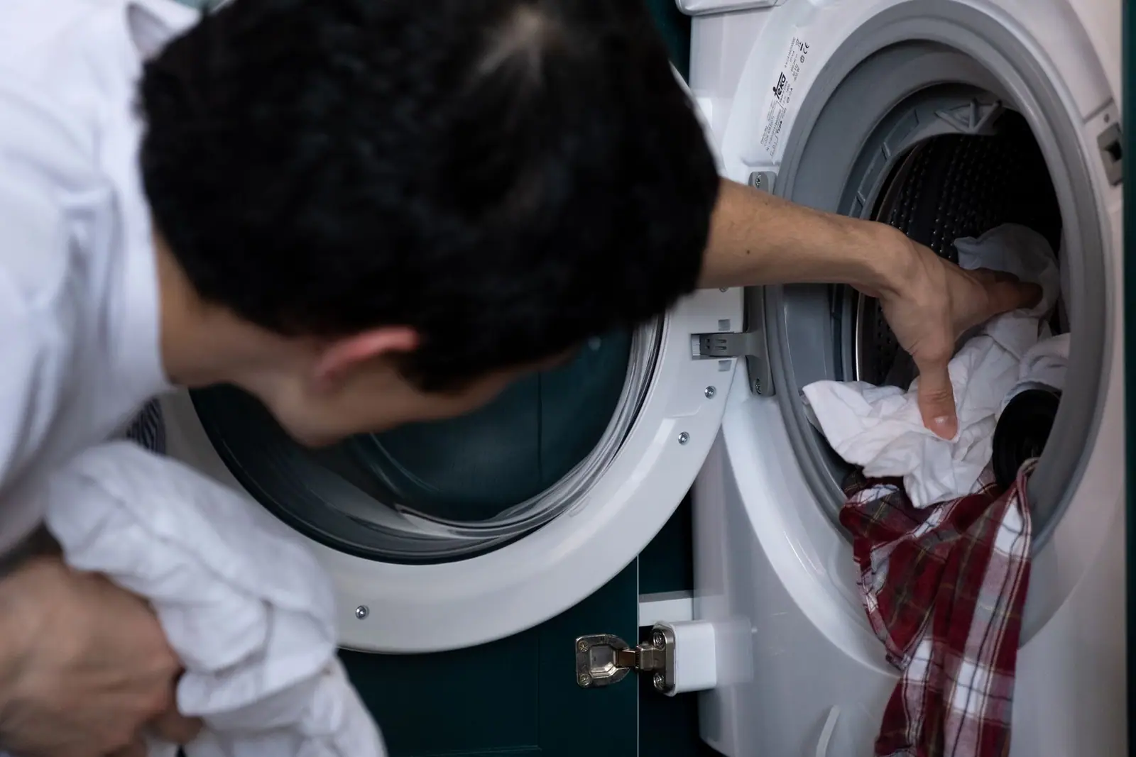 A person loading clothes into a front-loading washing machine