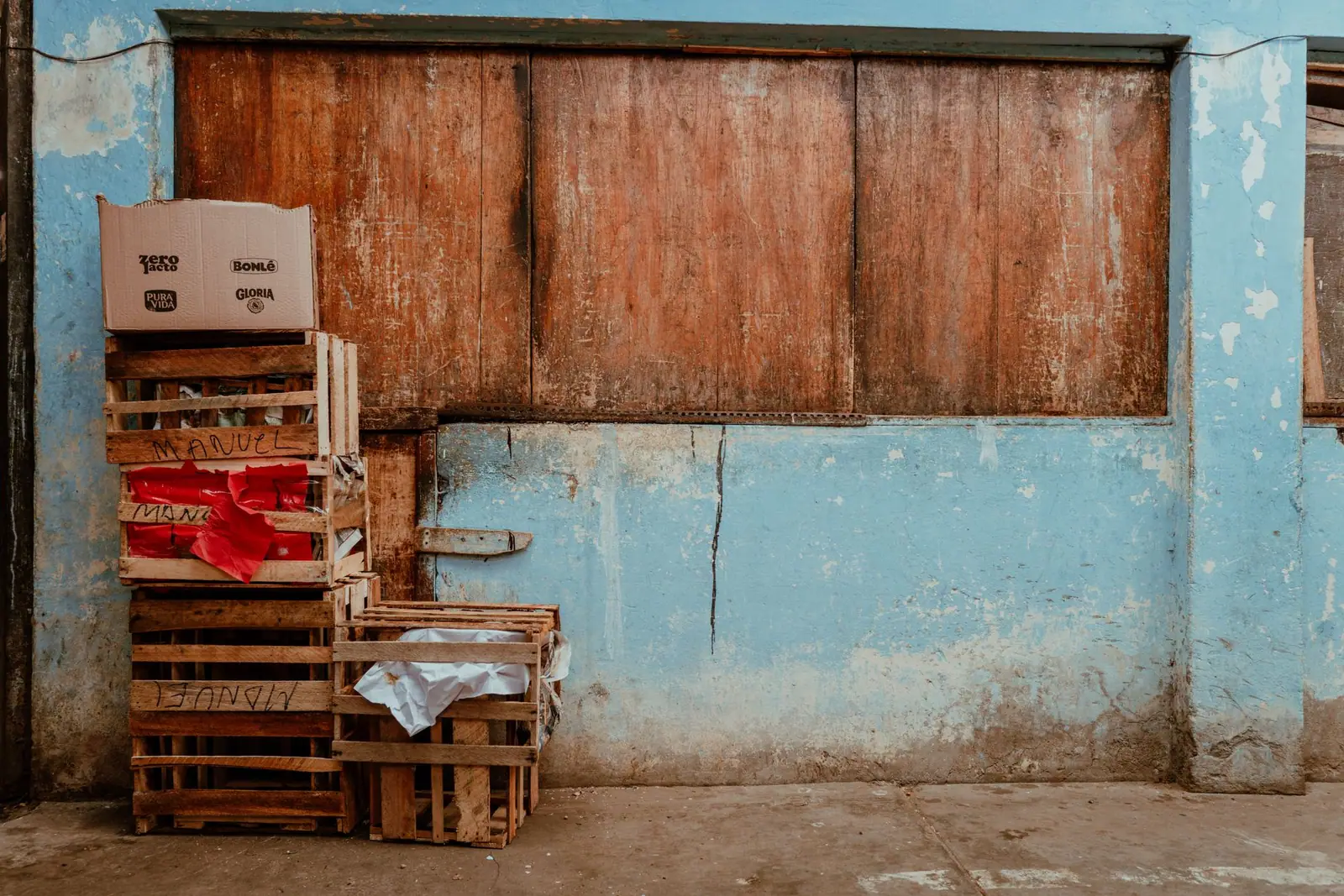 Wooden crates and cardboard boxes stacked against a weathered blue wall