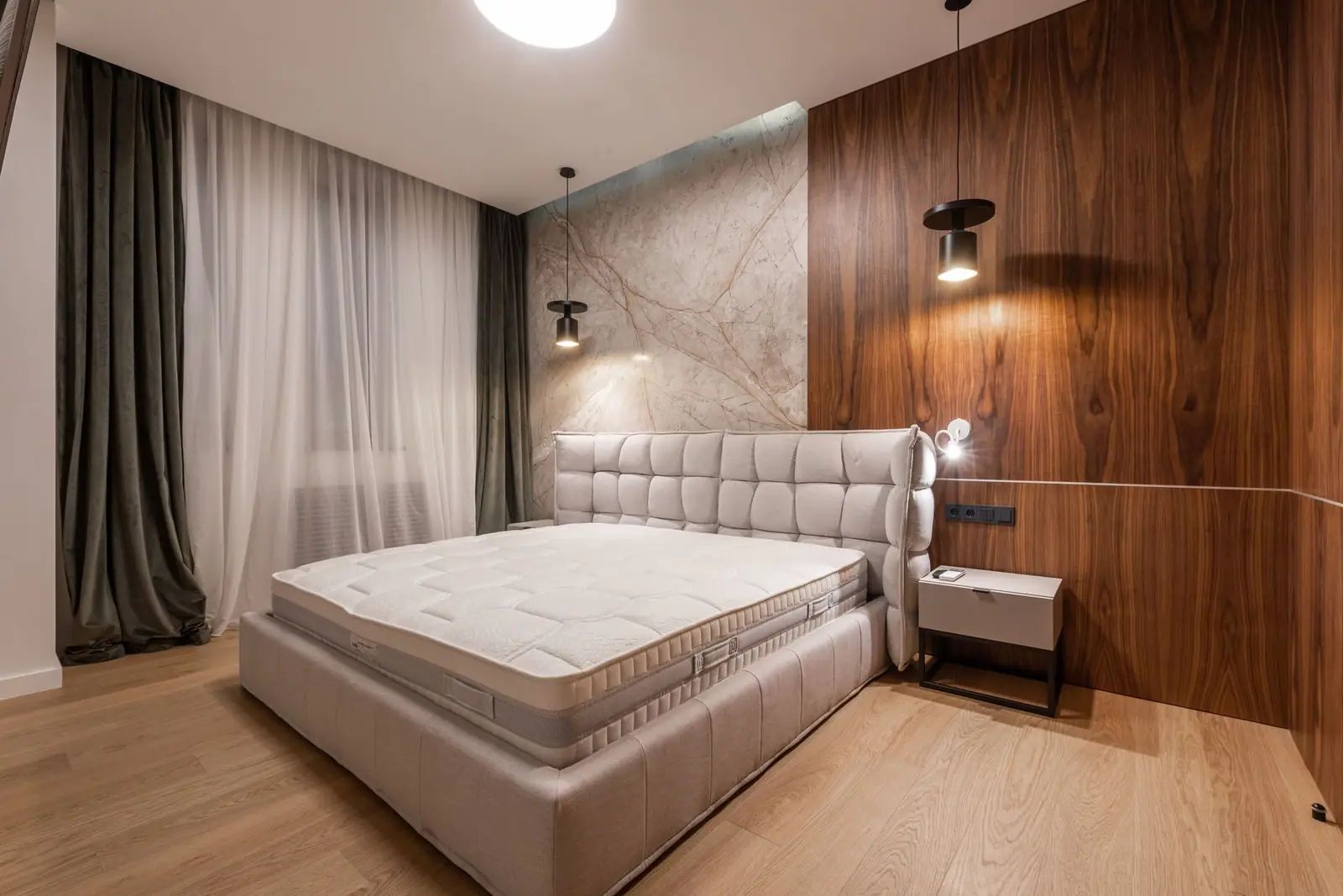A white quilted mattress on a bed in a bedroom with dark wood wall panels