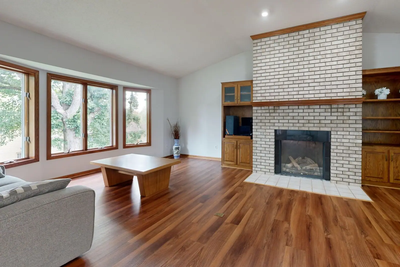 A white brick fireplace with a dark firebox in an empty room