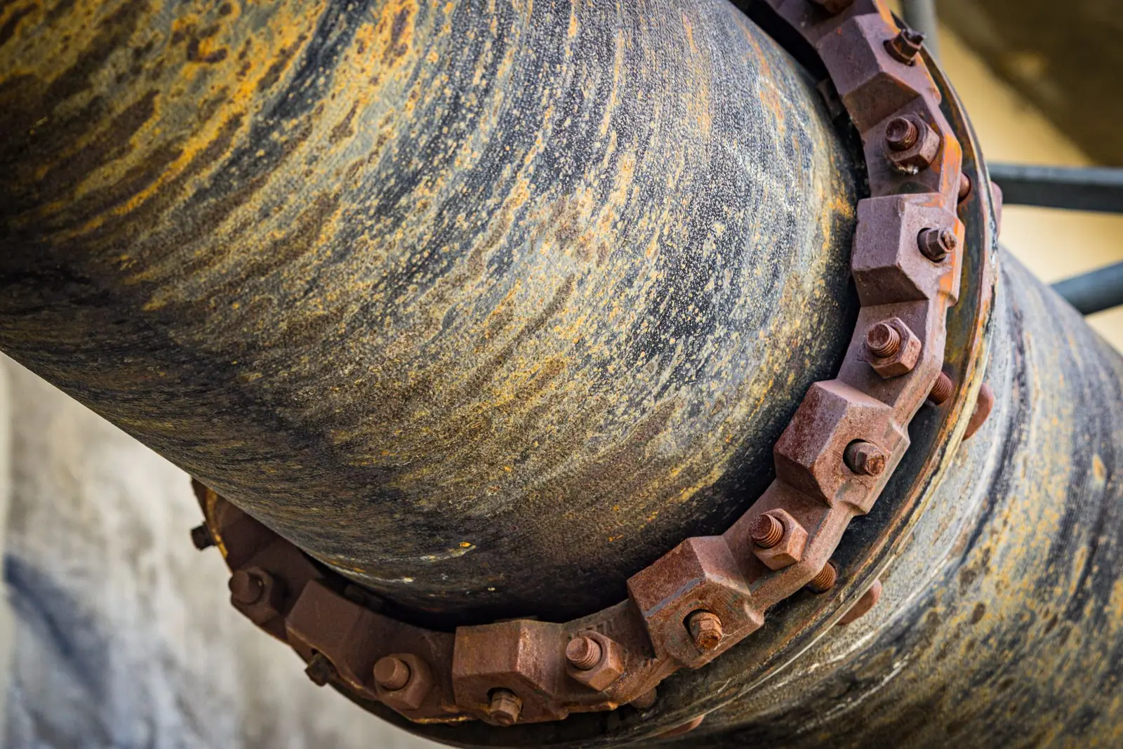 A weathered metal pipe with a bolted flange