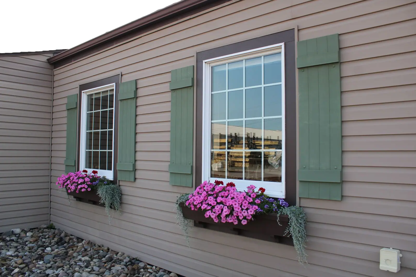A house with green window shutters and flower boxes beneath the windows