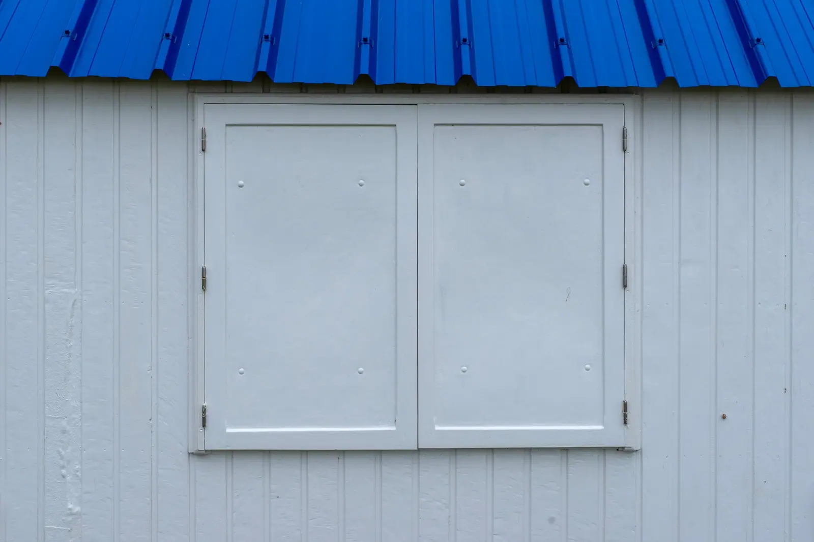 A boarded and shuttered window on the side of a house