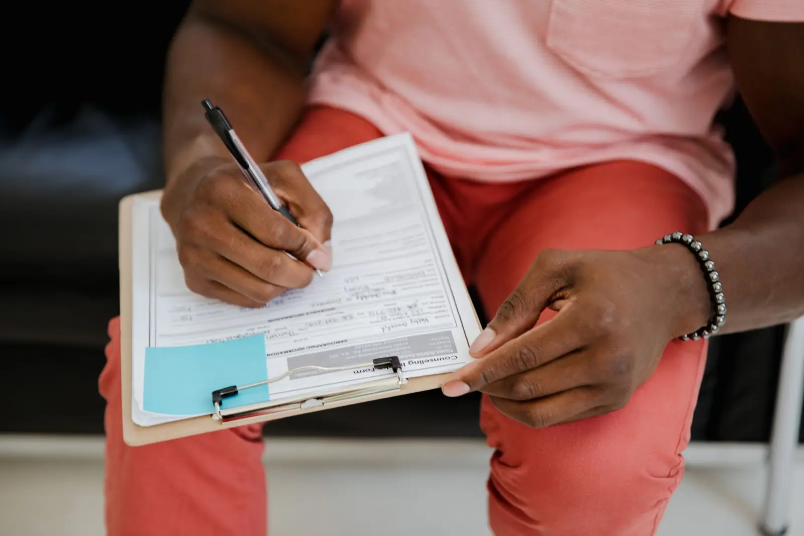 A hand writing on a form attached to a clipboard