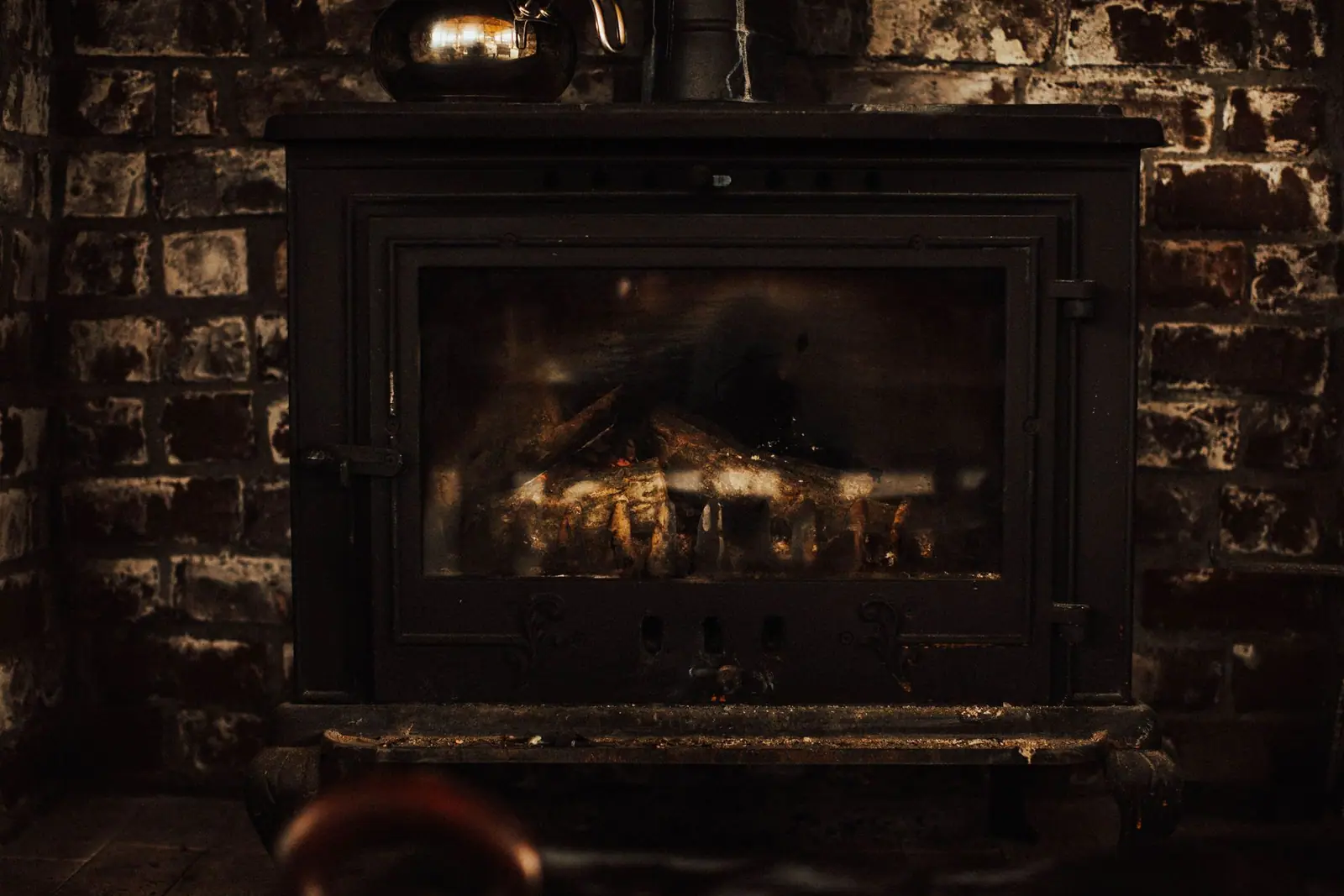 A black stove set into a brick fireplace opening