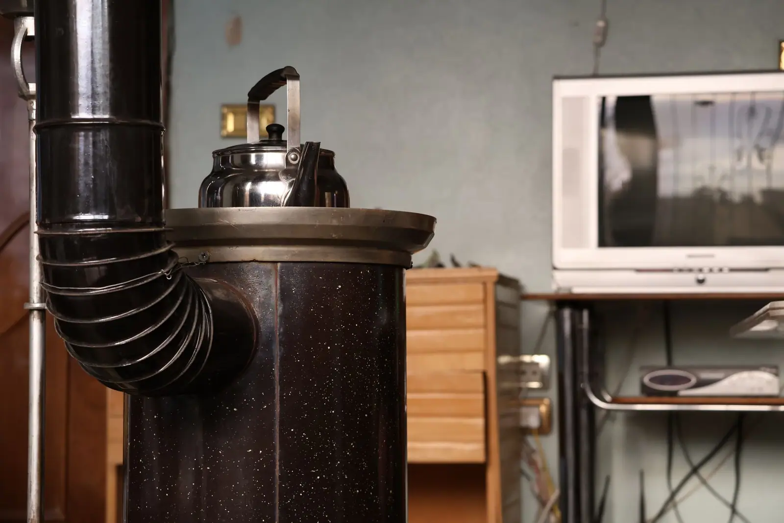 A stove with a corrugated flue pipe bending into the wall