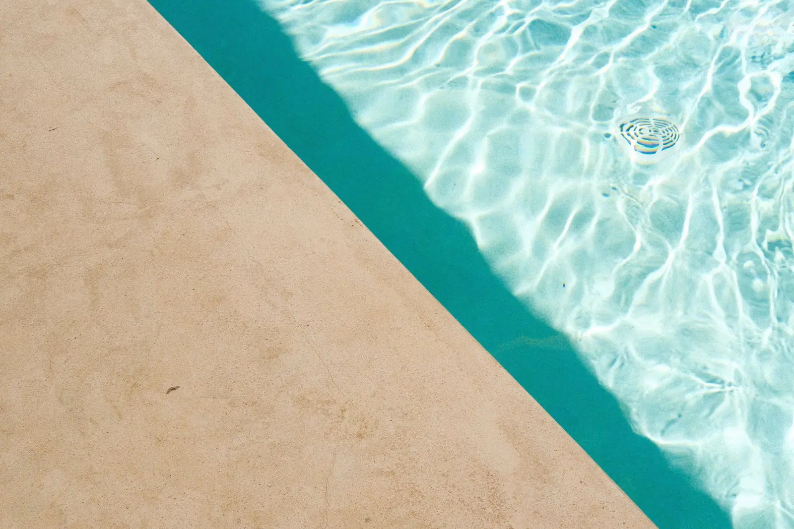 Blue swimming-pool water beside a pale stone coping edge