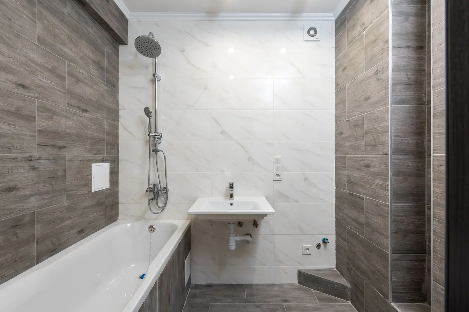 A tiled bathroom shower area with a window and shower fittings