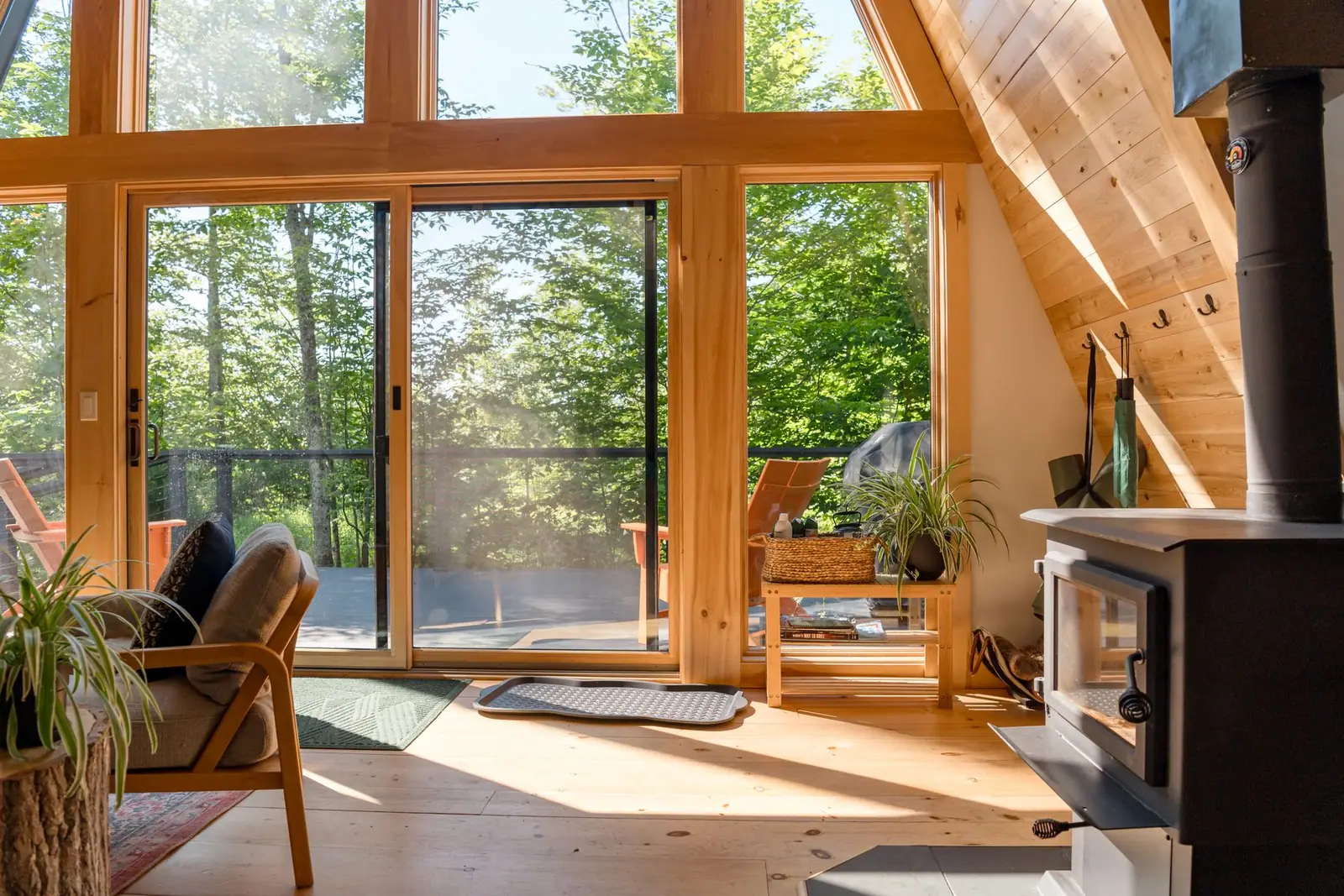 A wood stove in the corner of a sunlit A-frame cabin