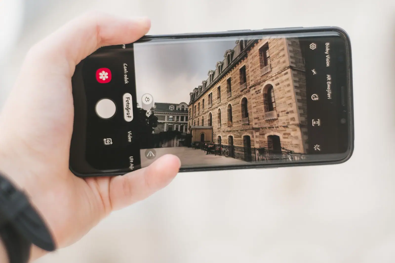 A hand holding a smartphone with a building on its screen