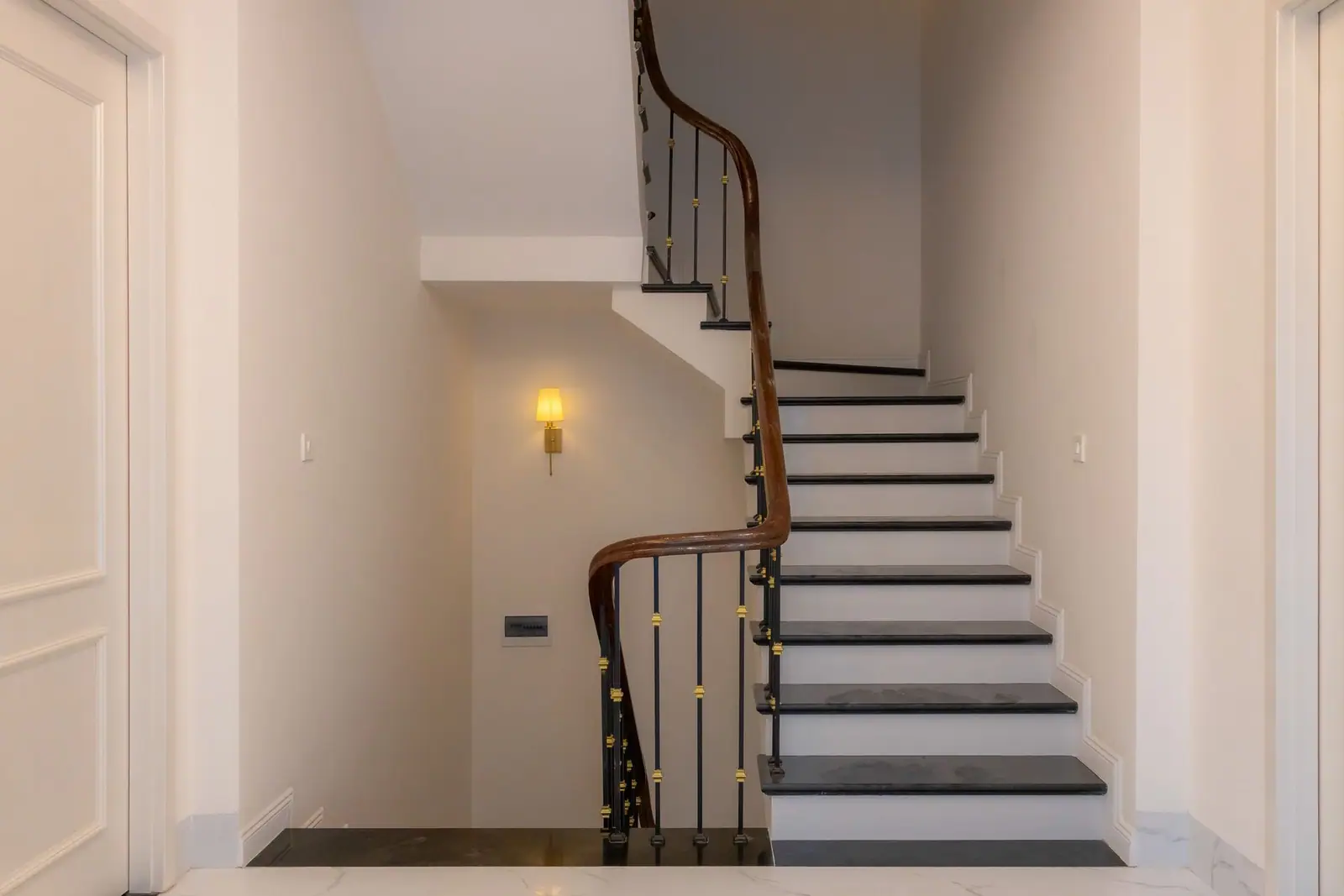 A staircase rising from a hallway beside a doorway
