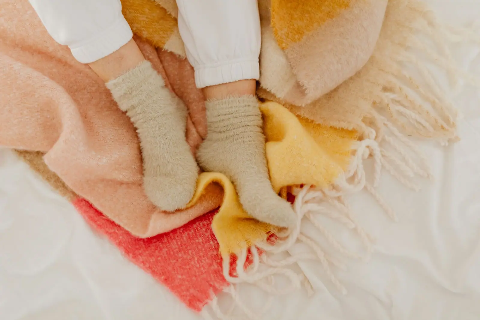 Feet in wool socks resting on folded woollen blankets